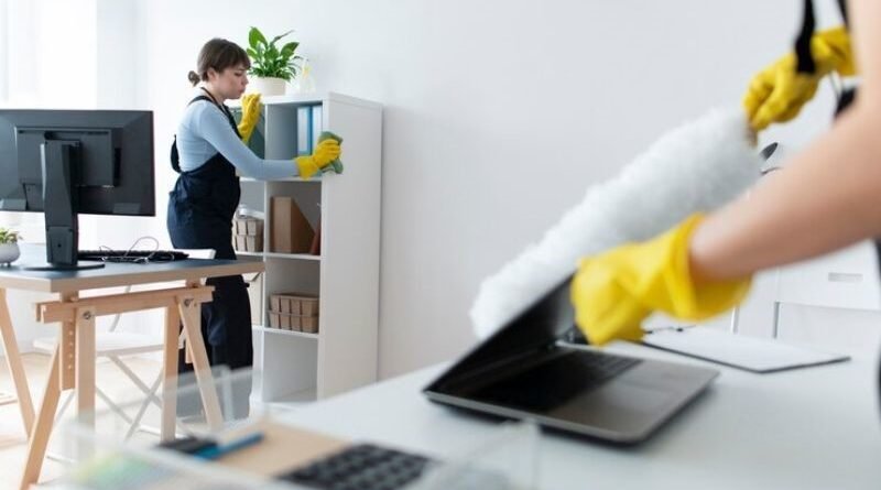 Mulheres funcionárias de Terceirização de Limpeza profissional, usando luvas e flanelas, limpando escritório.